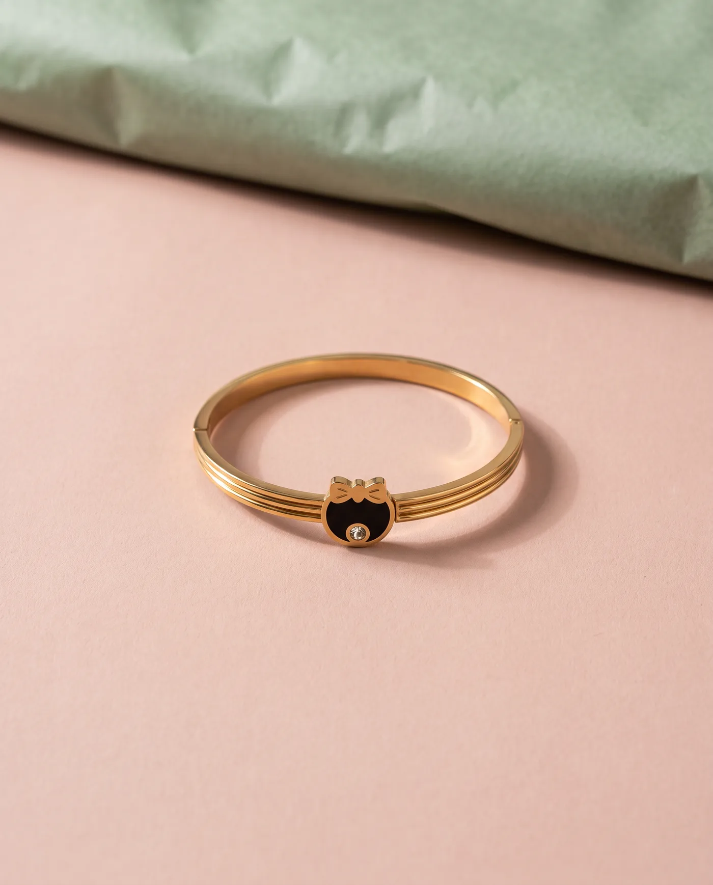 Bow Medallion Bangle: Ribbed gold band, black medallion