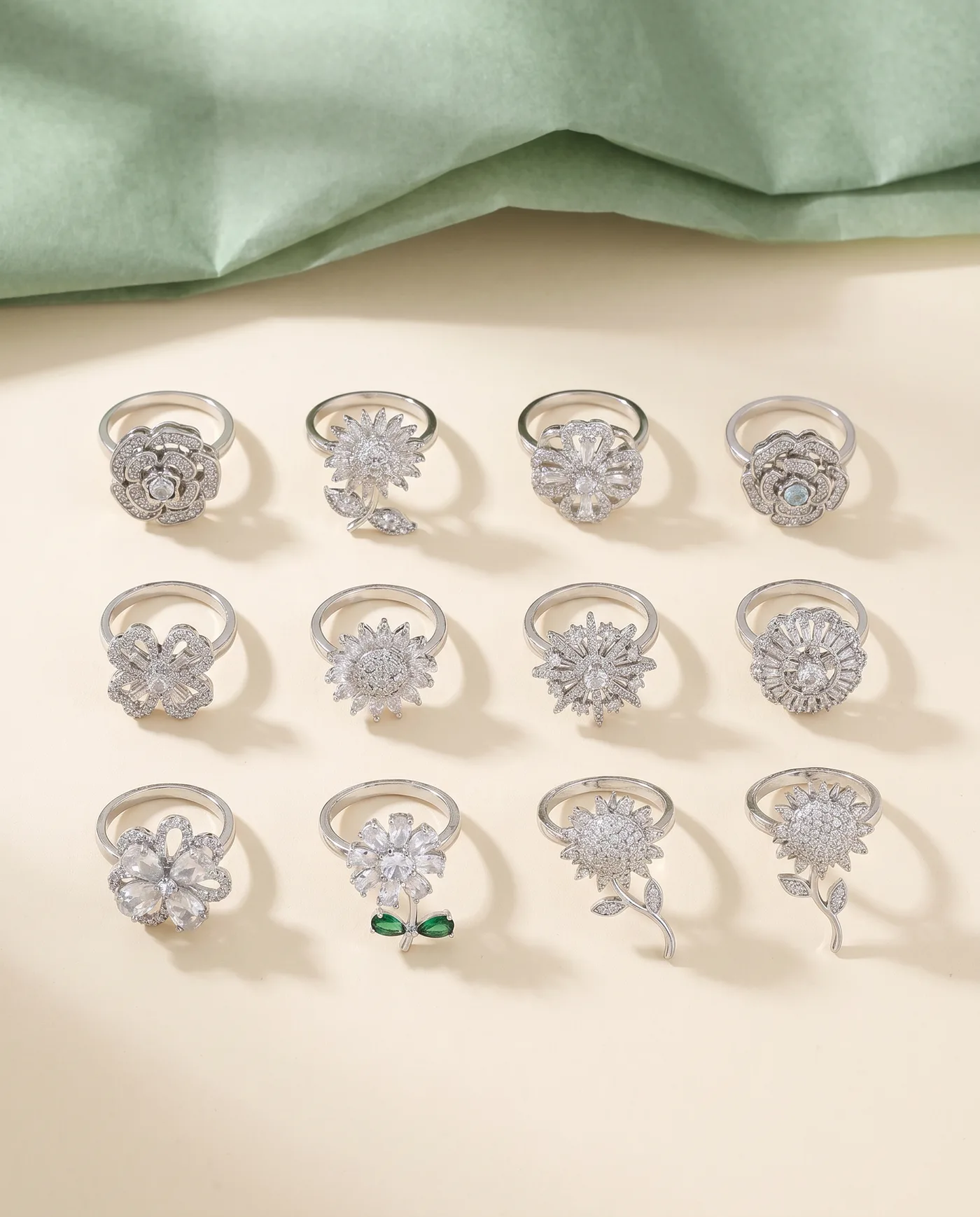 Twelve silver-tone spinner rings with crystal flower tops laid out on cream card